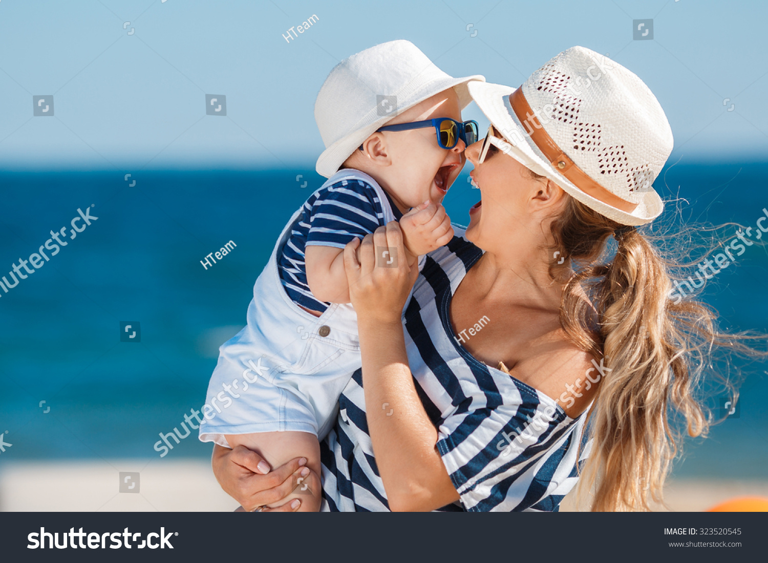 Happy family relaxing by the sea. Happy family resting at beach in summer. mother with baby boy resting on the beach. Young mother and her adorable little daughter on beach vacation #323520545