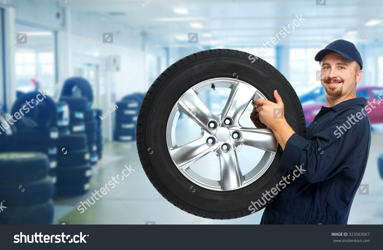 Smiling repairman with tire a in car repair service. #323563067