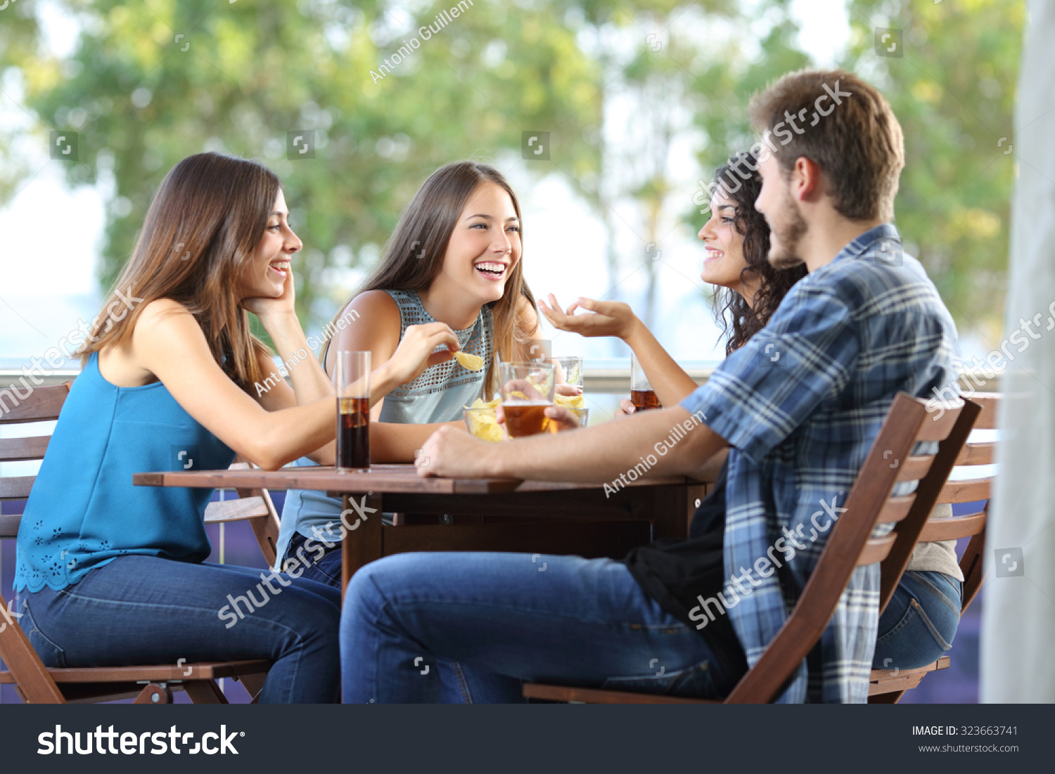 Group of four friends talking and drinking sitting in a terrace at home #323663741