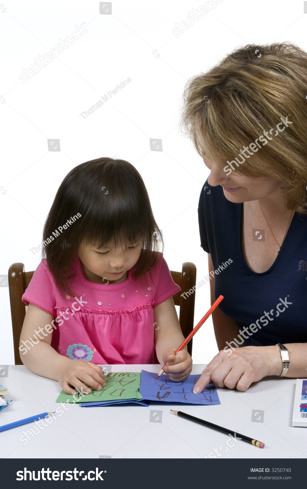 A young girl learns to write with the help of a teacher. #3250740