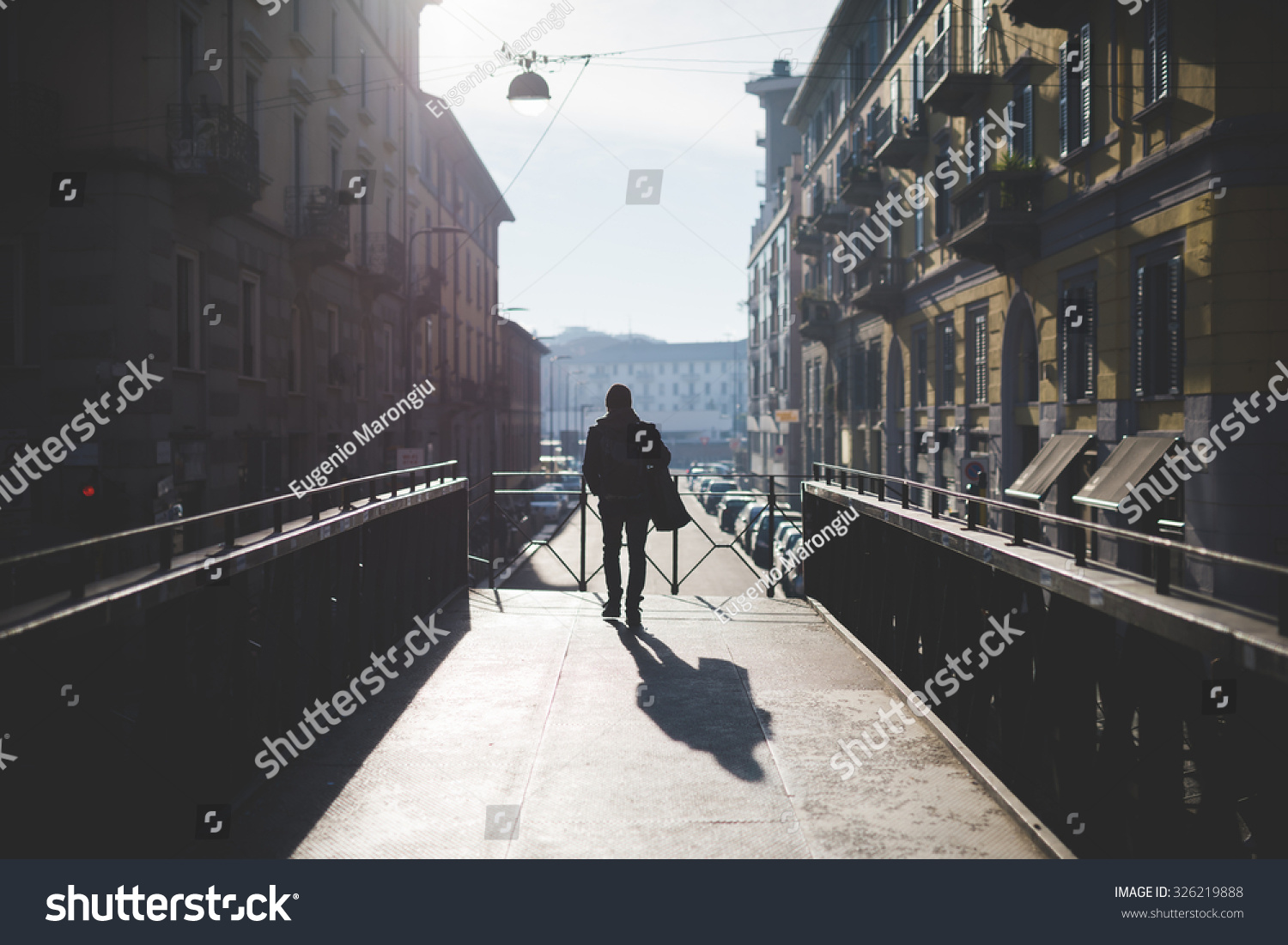 urban blurred landscape of Milan Navigli background during sunset in winter with a figure walking on a bridge #326219888