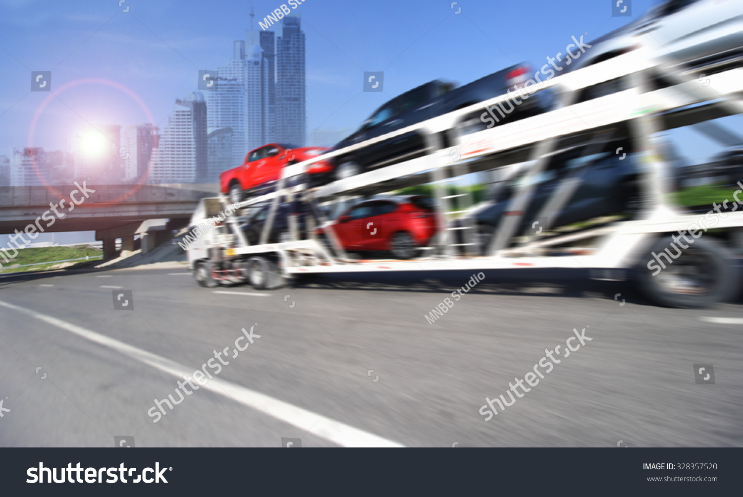 The trailer transports cars on highway with big city background  #328357520