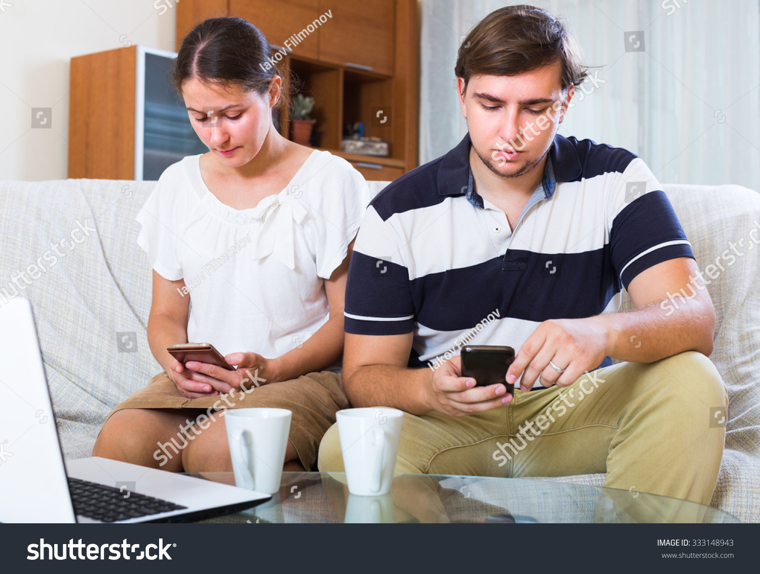 Young spouses burying in smartphones instead of talking indoors
 #333148943