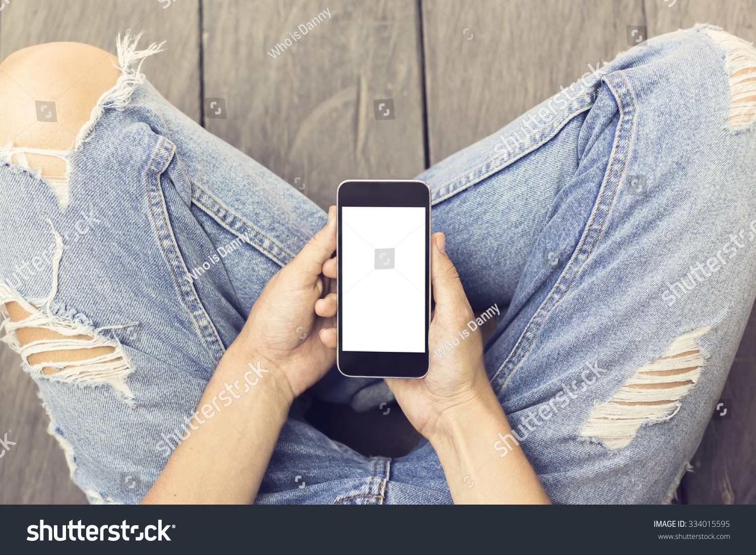 Girl in jeans with blank smartphone on the wooden floor, mock up #334015595