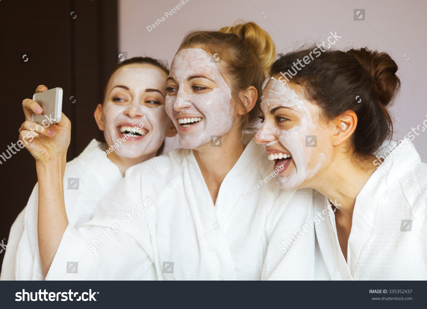 Three young happy women with face masks taking selfi at spa resort. Frenship and wellbeing concept #335352437