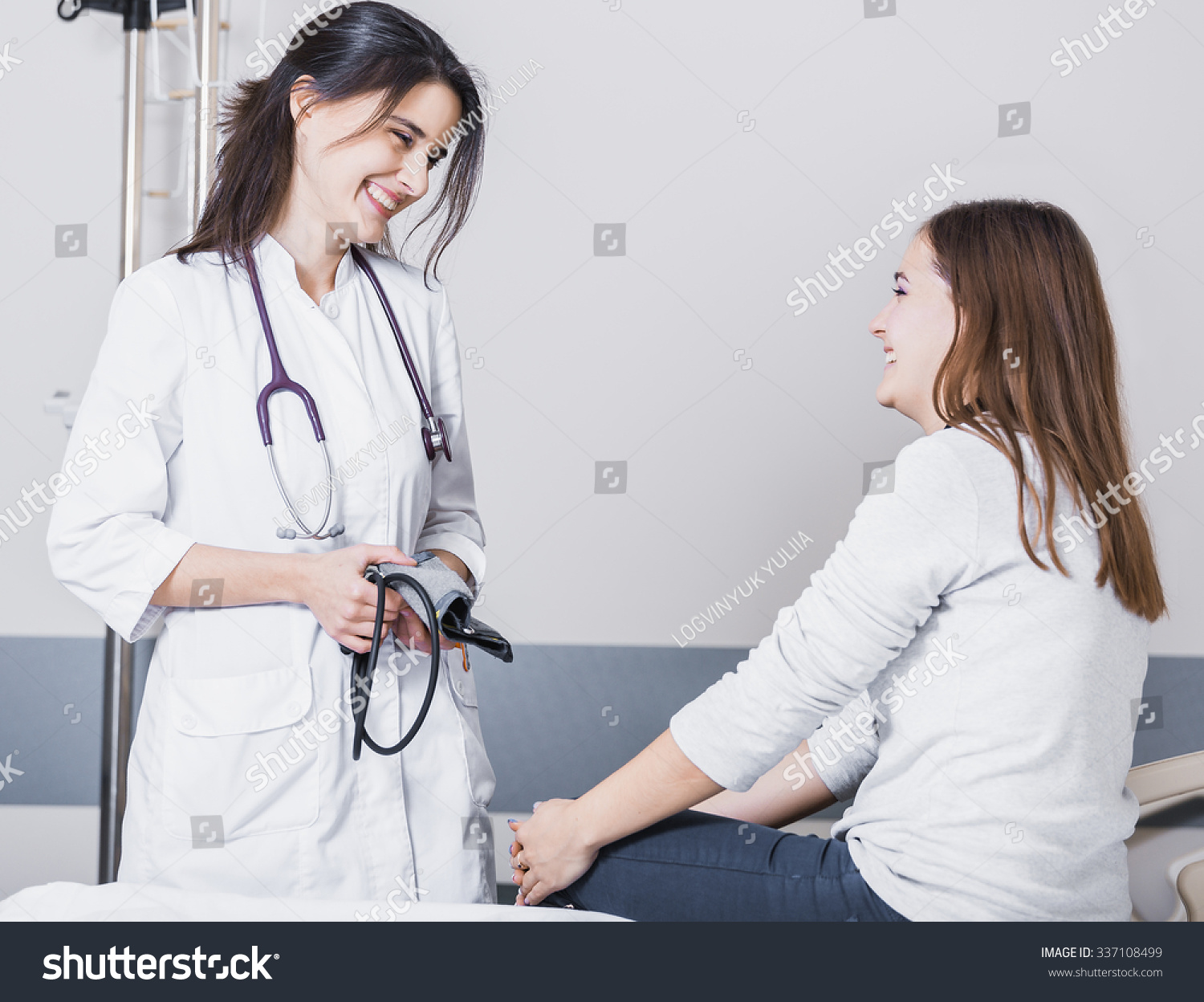 beautiful girl doctor in a white coat checks the blood pressure in the girl on the bed #337108499