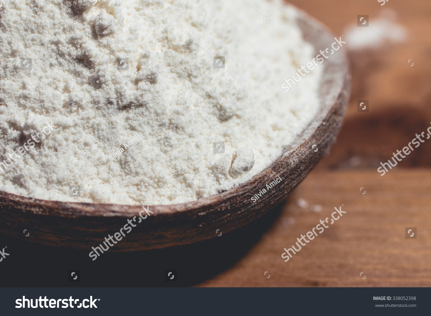 Wheat flour placed in a wooden spoon on the table #338052398