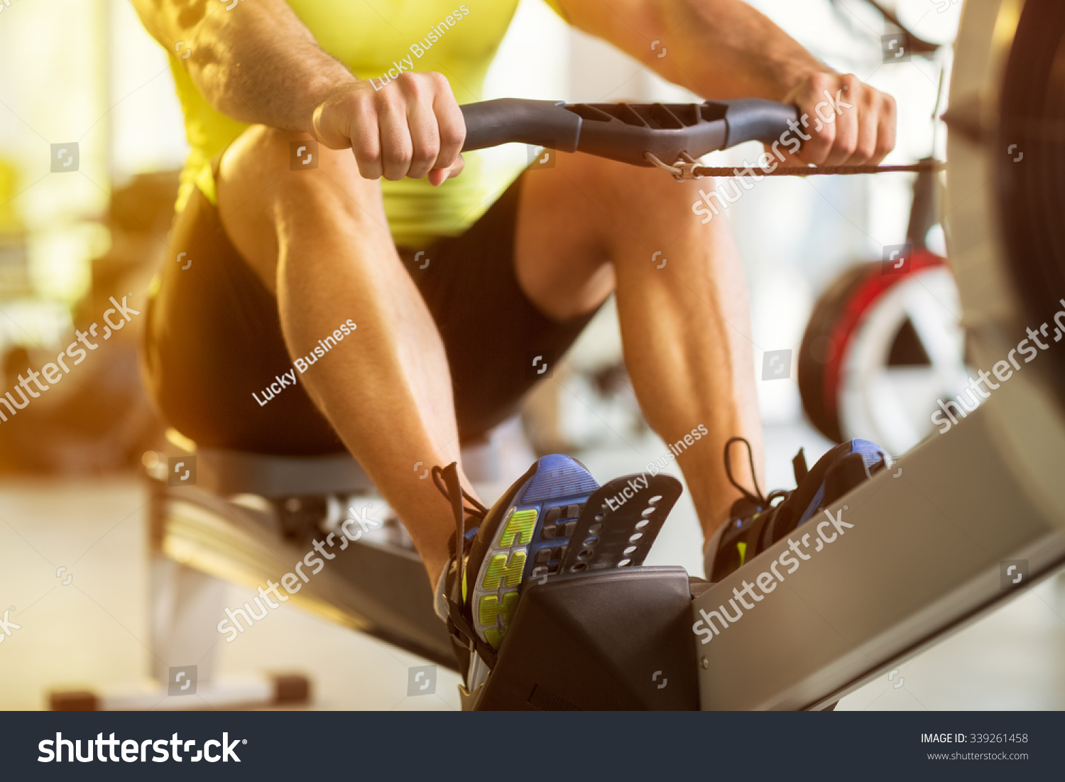 Fit man training on row machine in gym #339261458