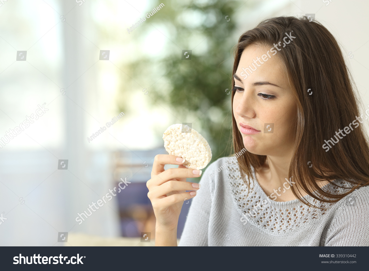 Girl disgusted looking a dietetic cookie. Bad diet concept #339310442