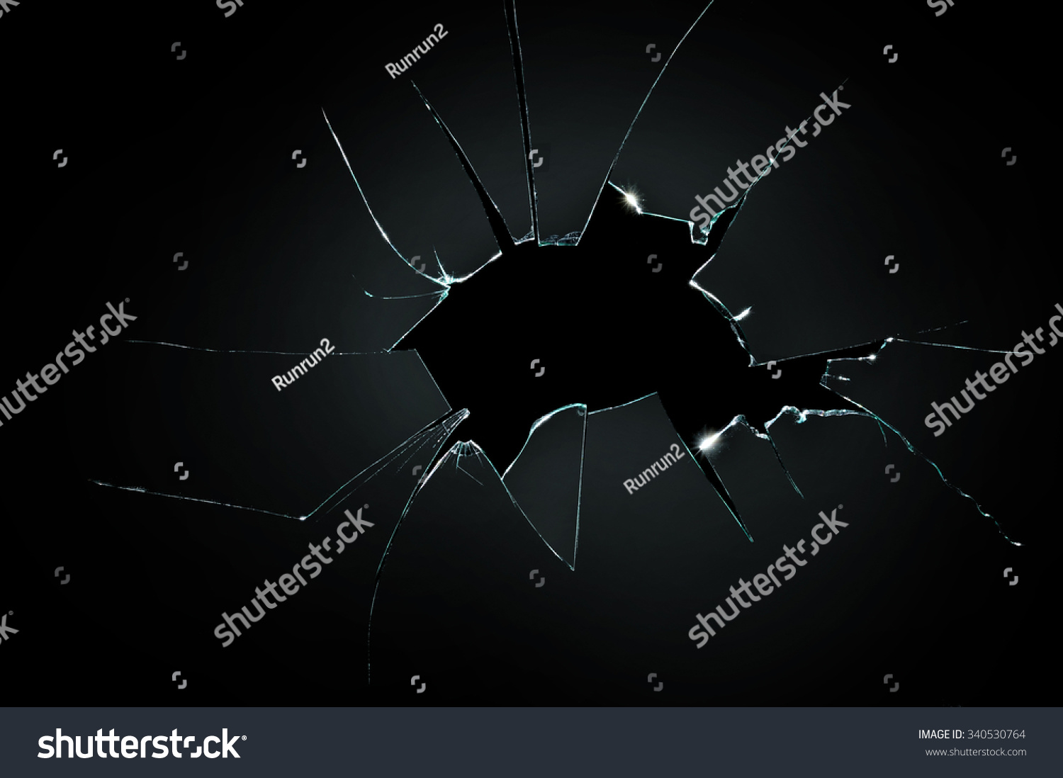 broken cracked glass with big hole over black background #340530764