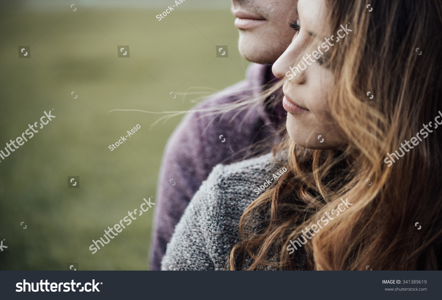 Young loving couple outdoors sitting on grass, hugging and looking away, future and relationships concept #341389619