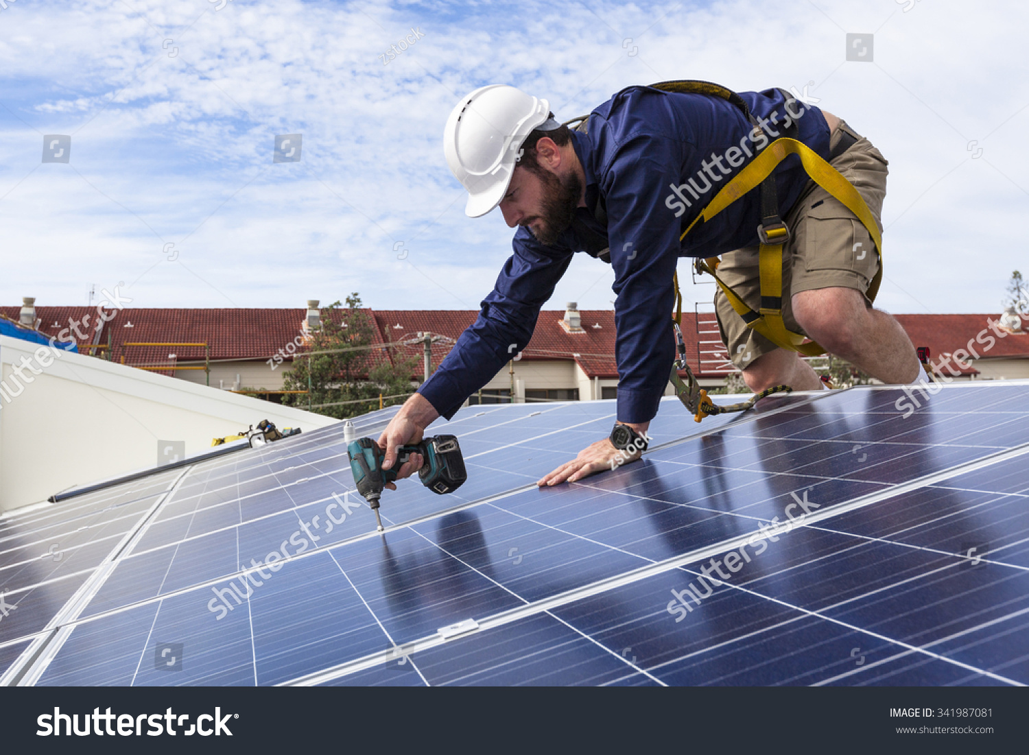 Solar panel technician with drill installing solar panels on roof #341987081