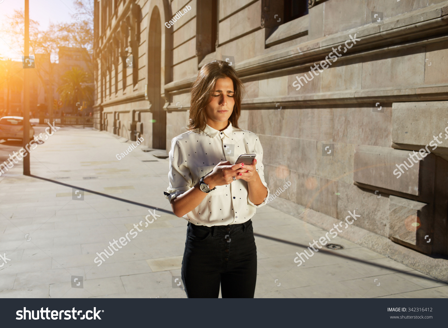 Portrait of nice hipster girl typing text message on her smart phone, young female using cellular phone while strolling in the city, woman using telephone with copy space area and your text message #342316412