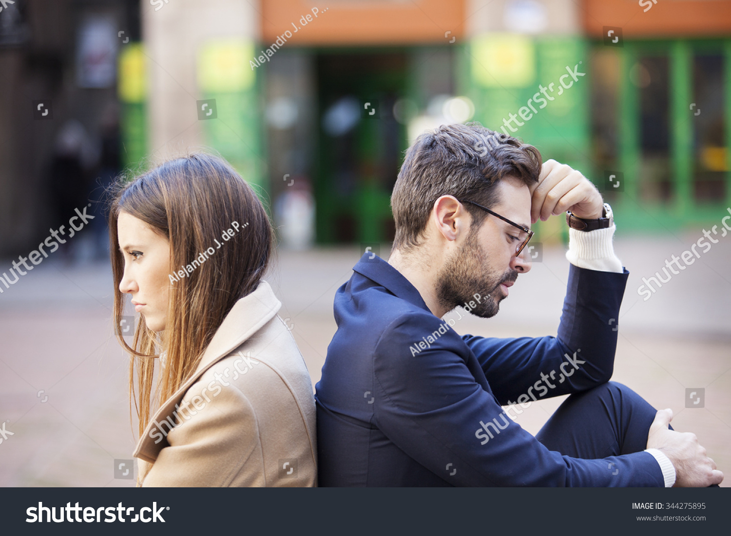 Bad relationship concept. Man and woman in disagreement. Young couple after quarrel sitting back to back. Outdoor
 #344275895