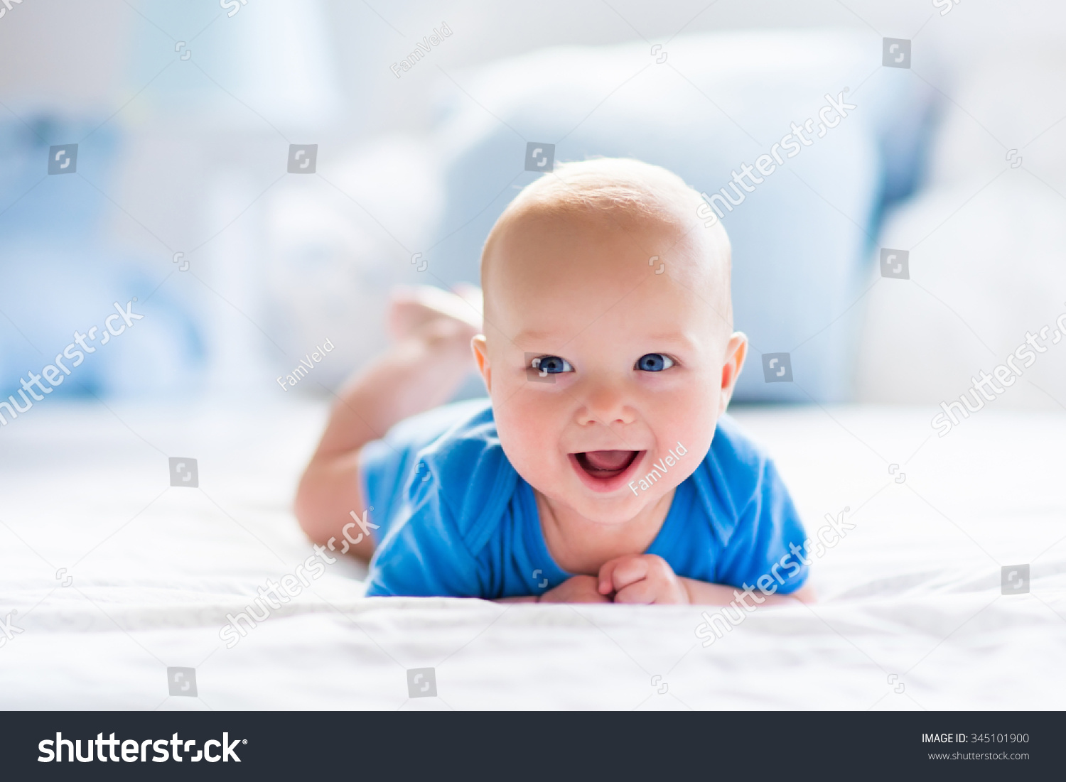 Adorable baby boy in white sunny bedroom. Newborn child relaxing in bed. Nursery for young children. Textile and bedding for kids. Family morning at home. New born kid during tummy time with toy bear. #345101900