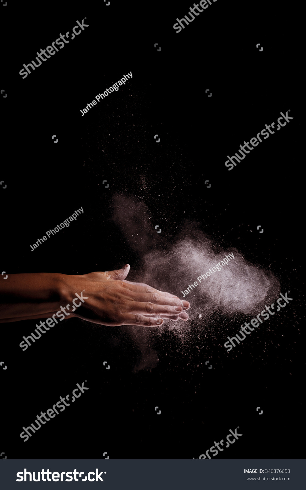 A woman beats her hands together, and white flour fly through the air. The shutter speed has been very fast. Image includes a effect. #346876658