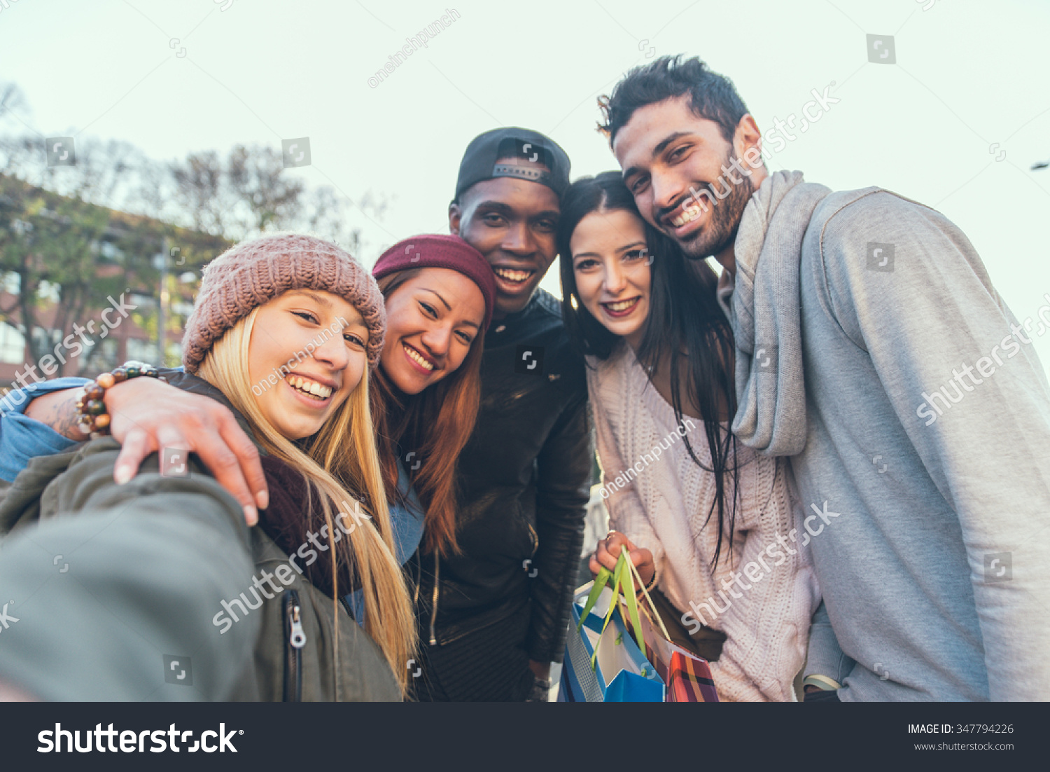 Multi-ethnic group of friends taking a selfie with cellphone outdoors - Young people photographing themselves #347794226