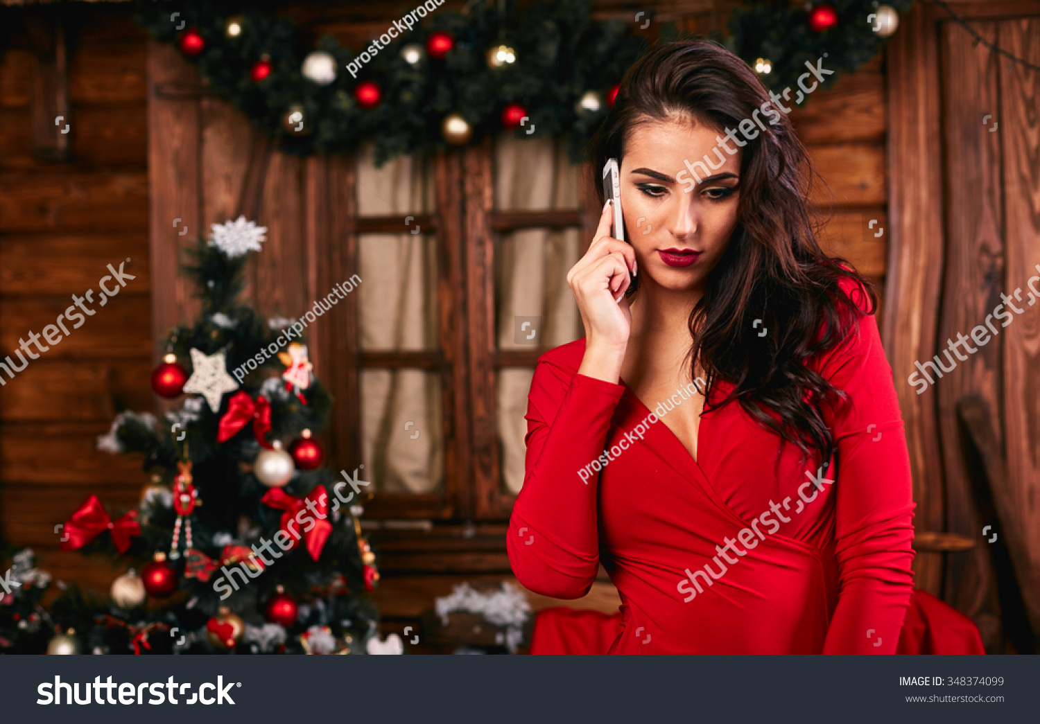 Young woman in red  dress  talking on mobile phone at Christmas decorated home #348374099