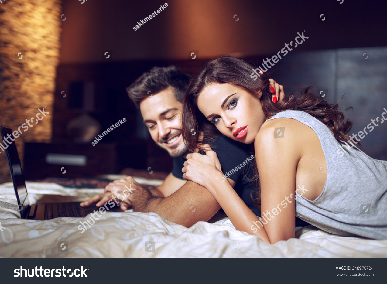 Young couple lying on bed with laptop, online shopping #348970724