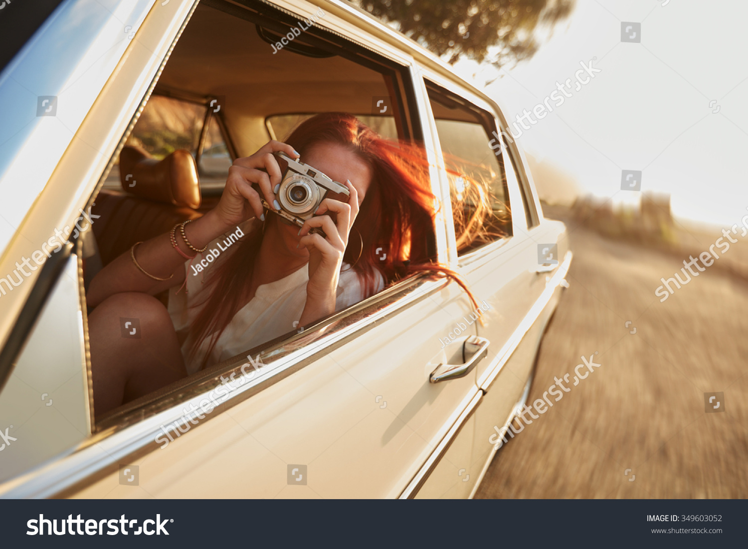 Shot of  young woman taking photos while sitting in a car. Female capturing a perfect road trip moment. #349603052