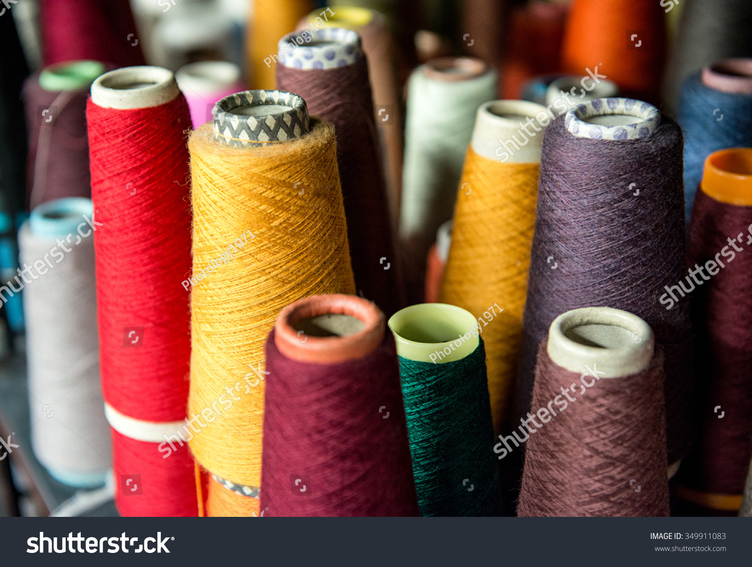 Colorful assortment of vivid colors of cotton spools on cardboard cones for use in the knitwear and garment industry viewed high angle #349911083