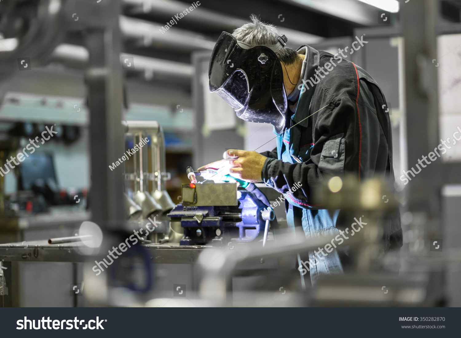Industrial worker with protective mask welding inox elements in steel structures manufacture workshop. #350282870