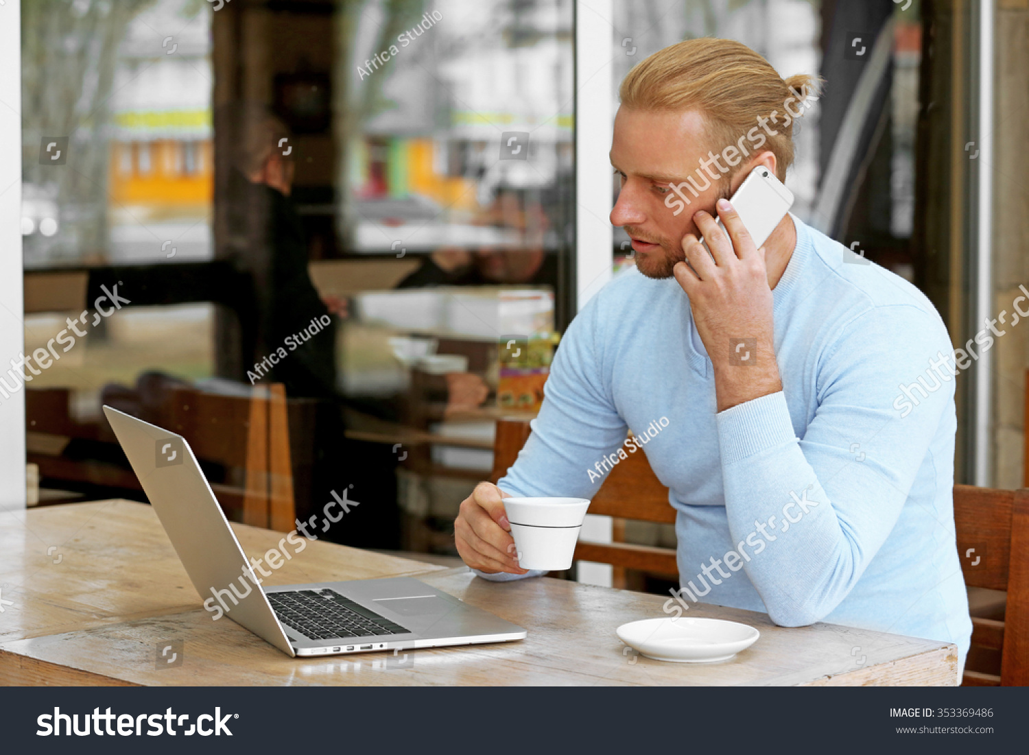 Young attractive businessman having lunch and working in a cafe #353369486