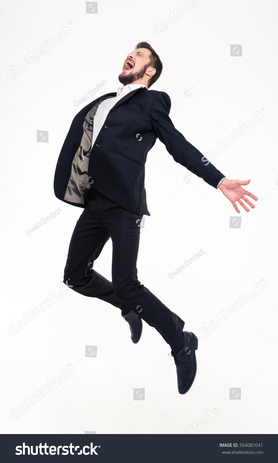 Excited elated happy young business man with beard in classic suit jumping and shouting over white background #354081041