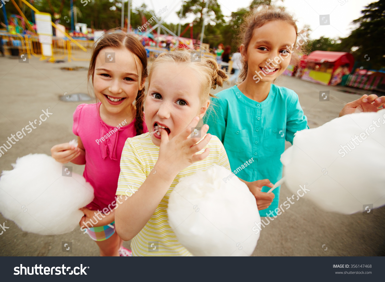 Happy girls eating cotton candy in the park #356147468