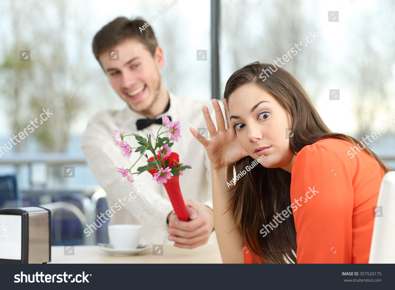 Disgusted woman rejecting a geek boy offering flowers in a blind date in a coffee shop interior #357520175