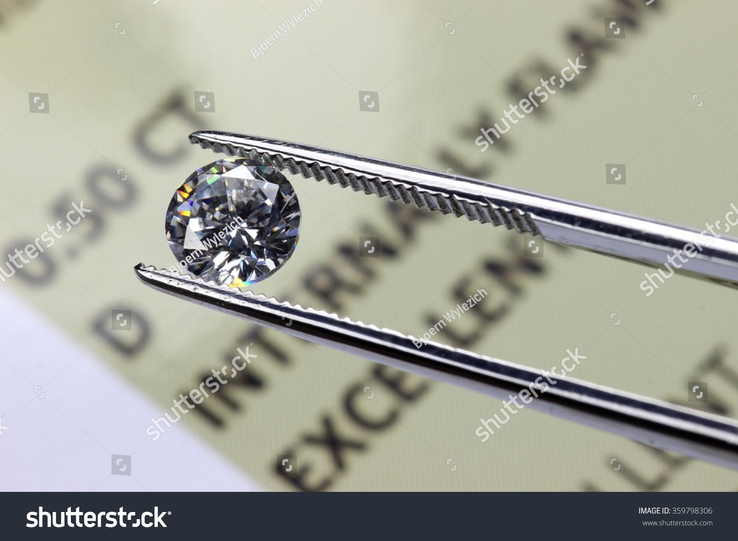 cut diamond held by tweezers above certificate #359798306