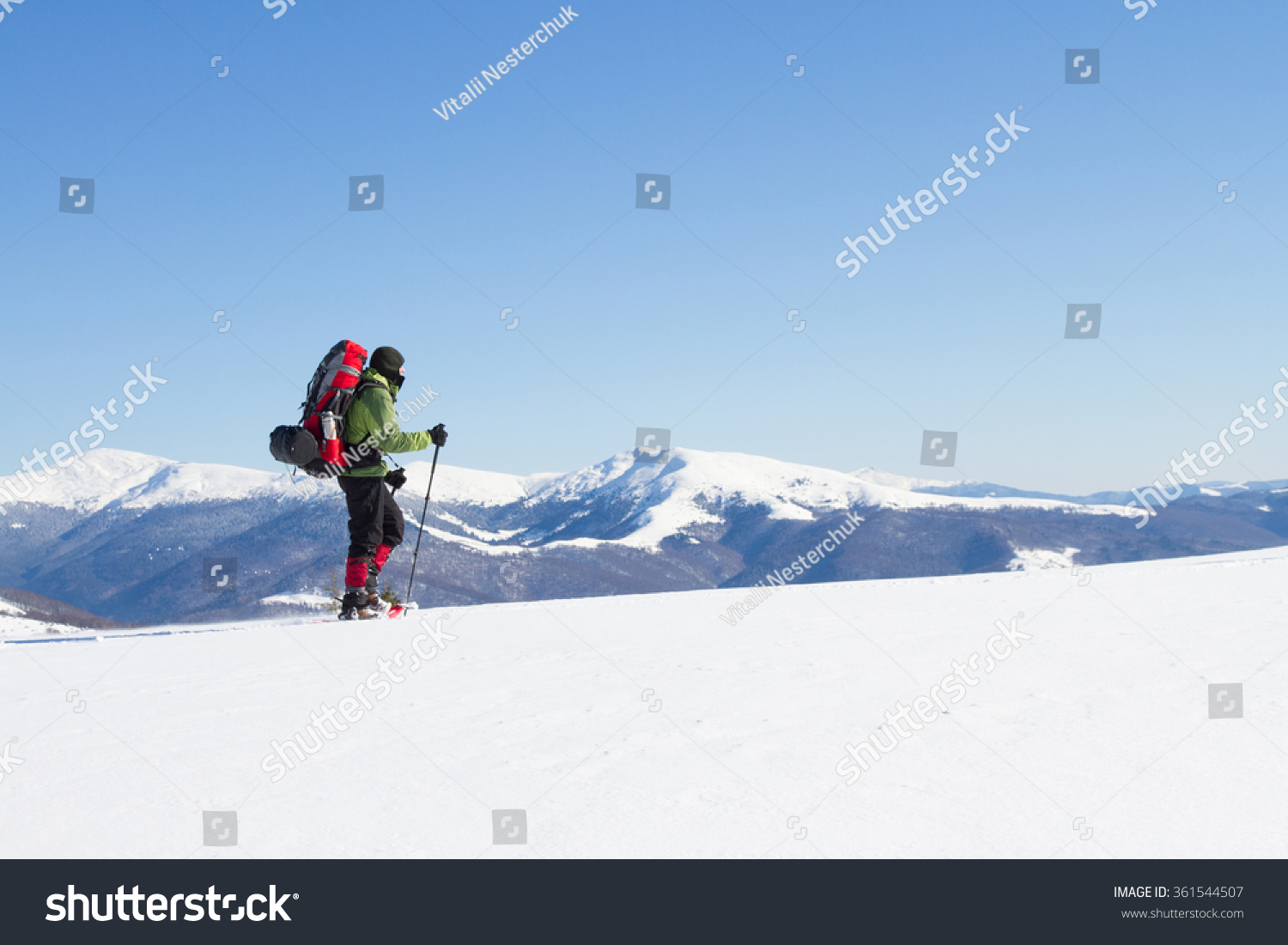 Winter hiking in the mountains on snowshoes with a backpack and tent. #361544507