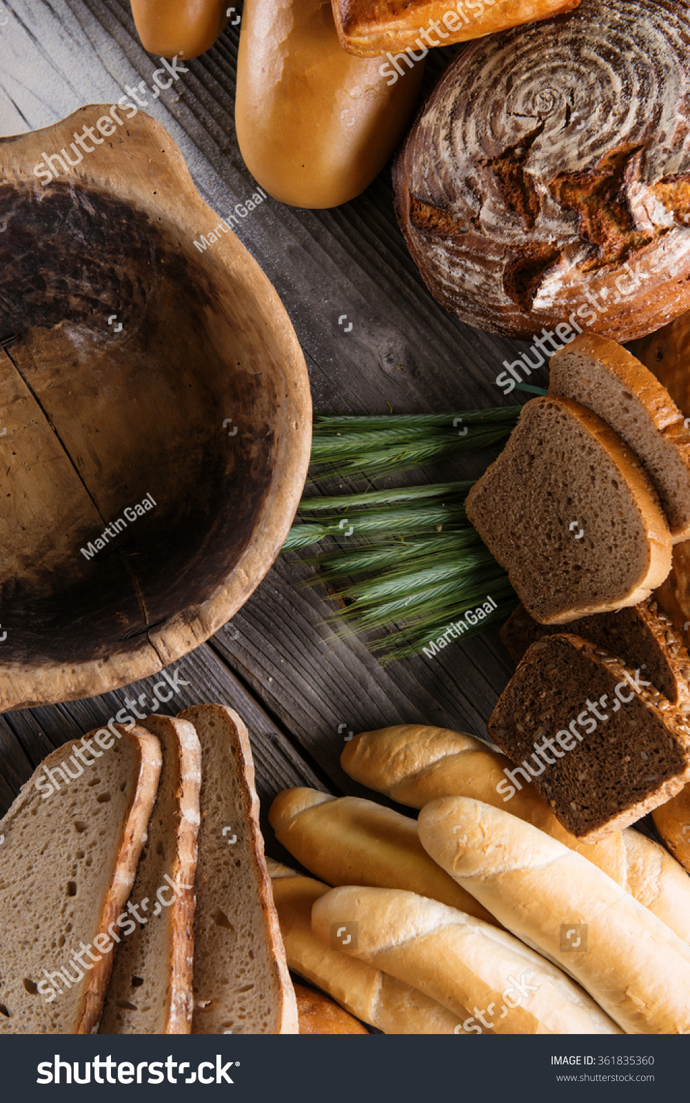 rolls and breads on wooden table with wooden bowl, background for bakery or market #361835360