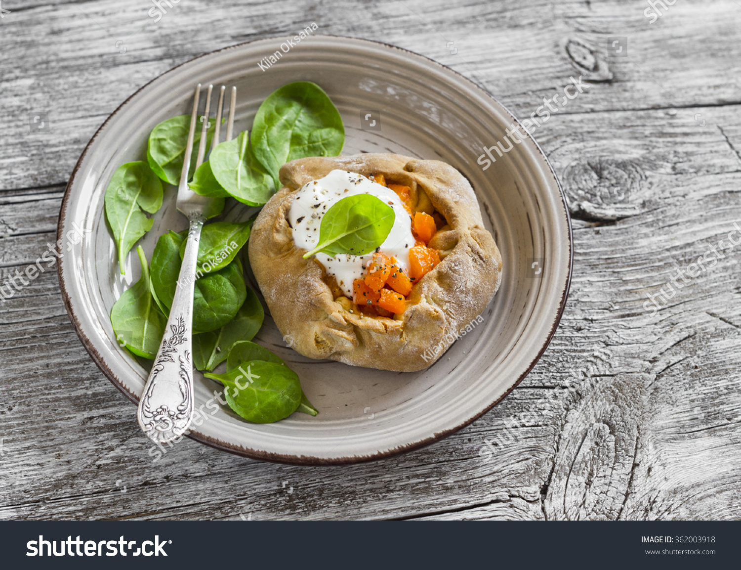 Savoury rustic pumpkin pie and fresh spinach on rustic light wood table. Delicious lunch, breakfast or snack #362003918