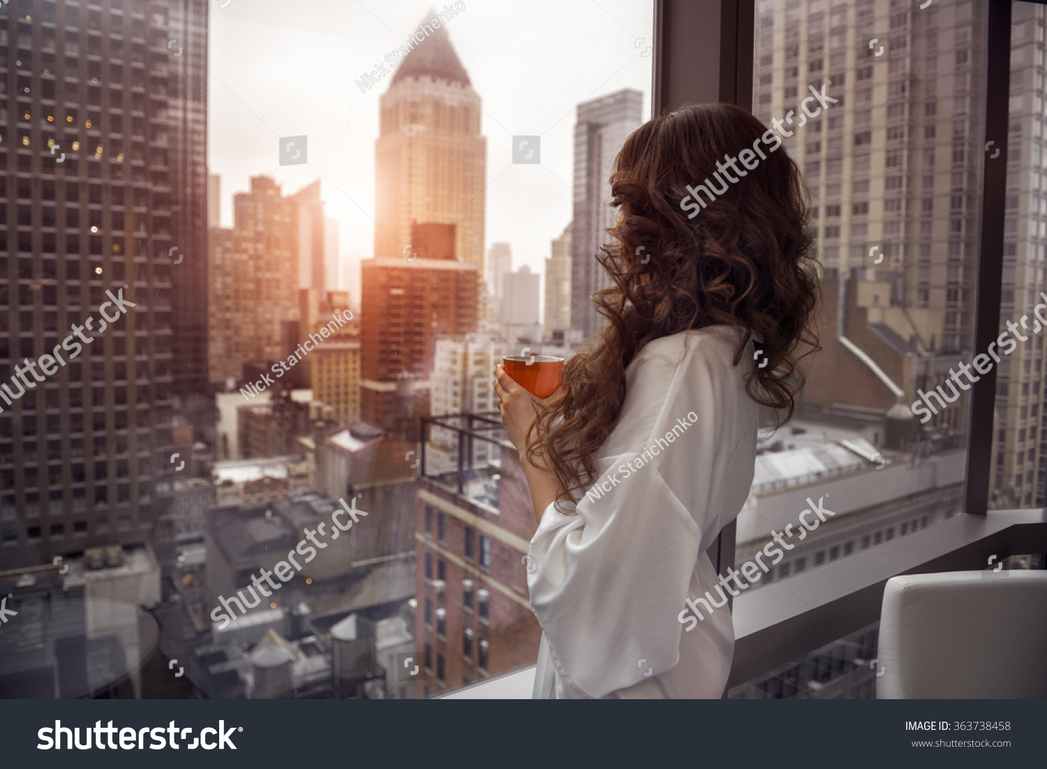 Beautiful woman holding coffee cup and looking to the window in luxury Manhattan penthouse apartments. Good morning after wake up. #363738458