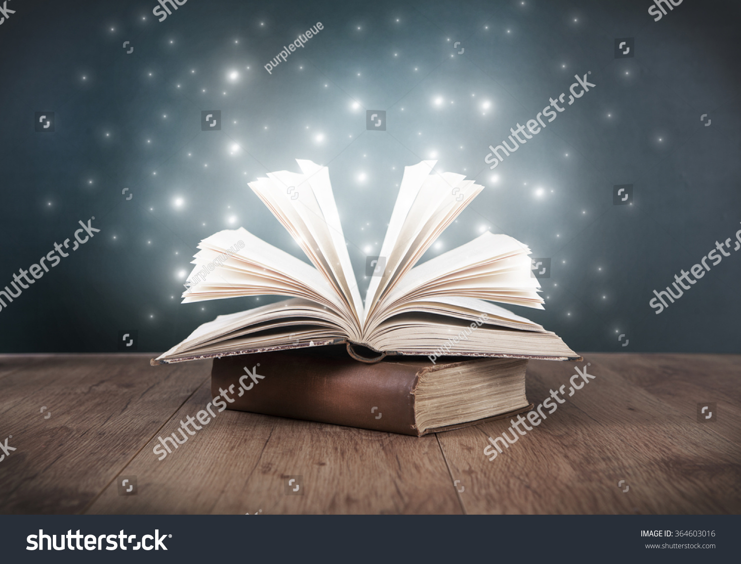 an old open book on a table in front of a blackboard #364603016