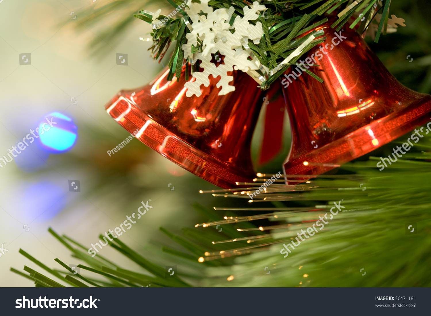Close-up of red toy bells hanging on green spruce branch decorated with paper snowflake #36471181