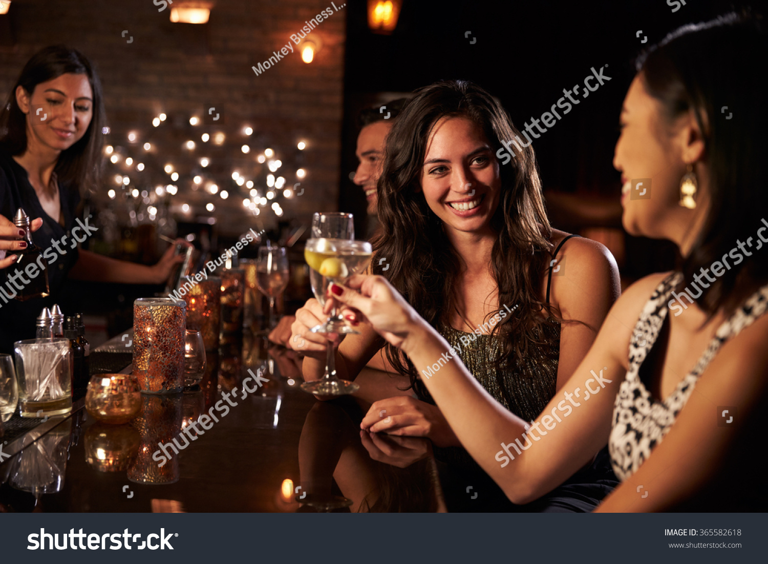 Female Friends Enjoying Night Out At Cocktail Bar #365582618