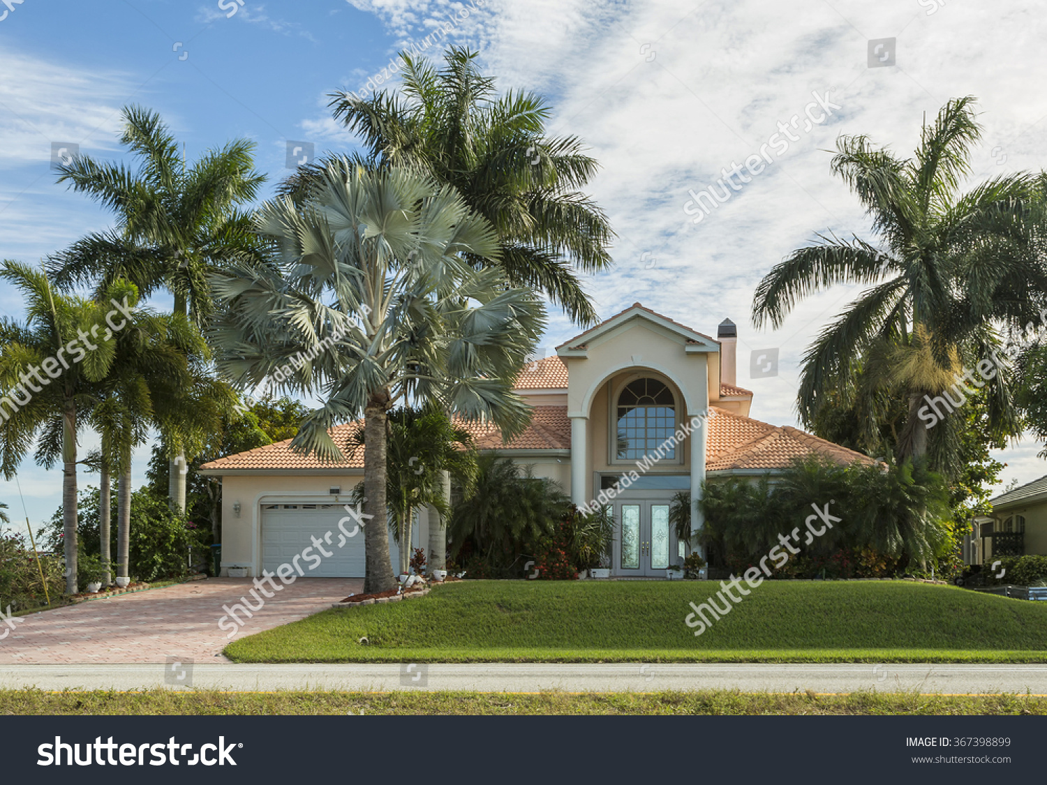 Typical Southwest Florida home in the countryside with palm trees, tropical plants and flowers, grass and pine trees. Inlaid pavement at the entrance. Florida #367398899