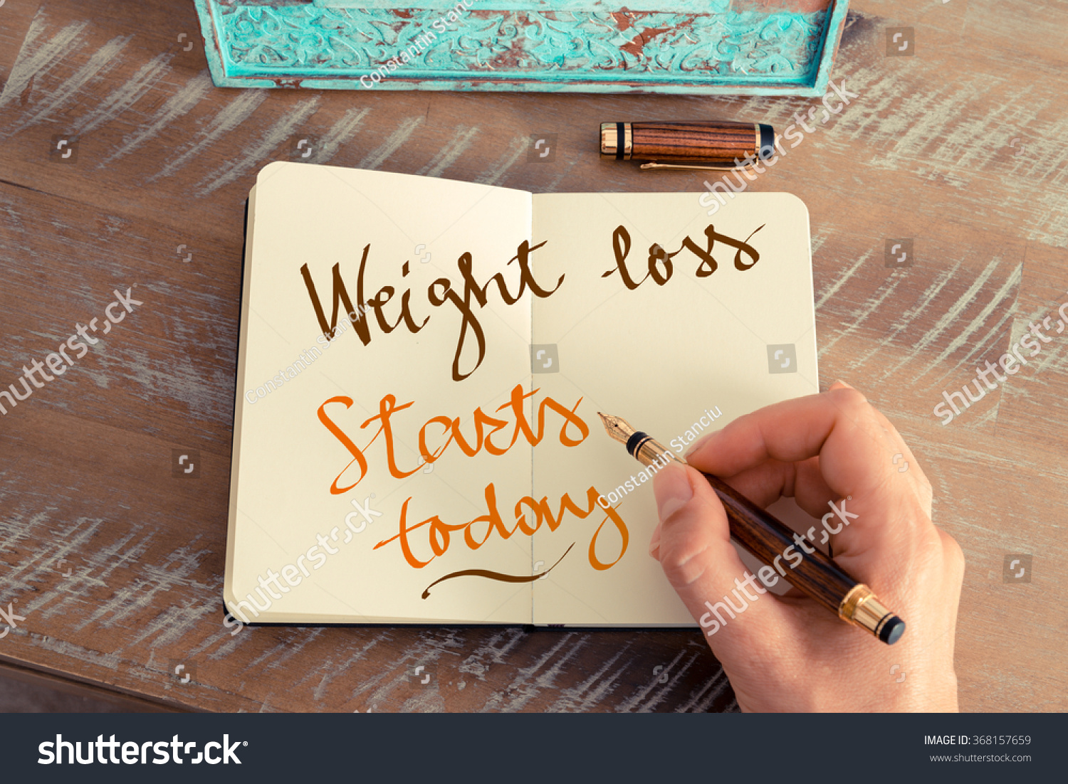 Retro effect and toned image of a woman hand writing a note with a fountain pen on a notebook. Handwritten text WEIGHT LOSS STARTS TODAY, motivation concept #368157659