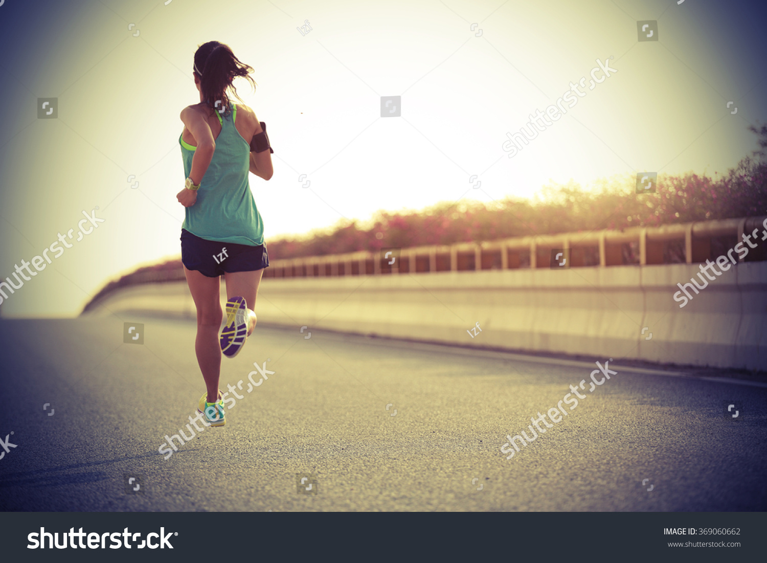 young fitness woman runner running on seaside bridge #369060662