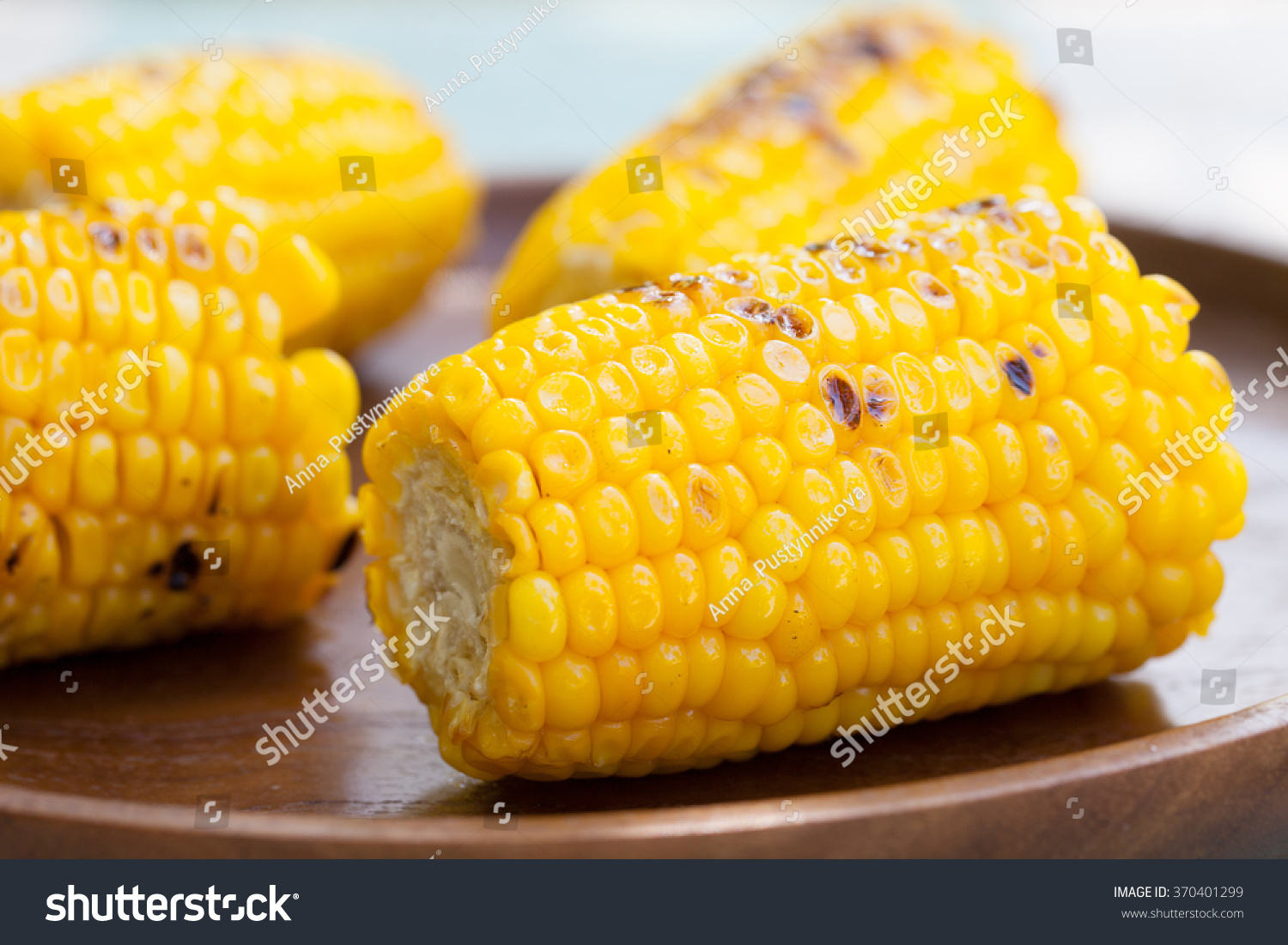 Grilled corn on the cob with salt and butter on a wooden plate  #370401299