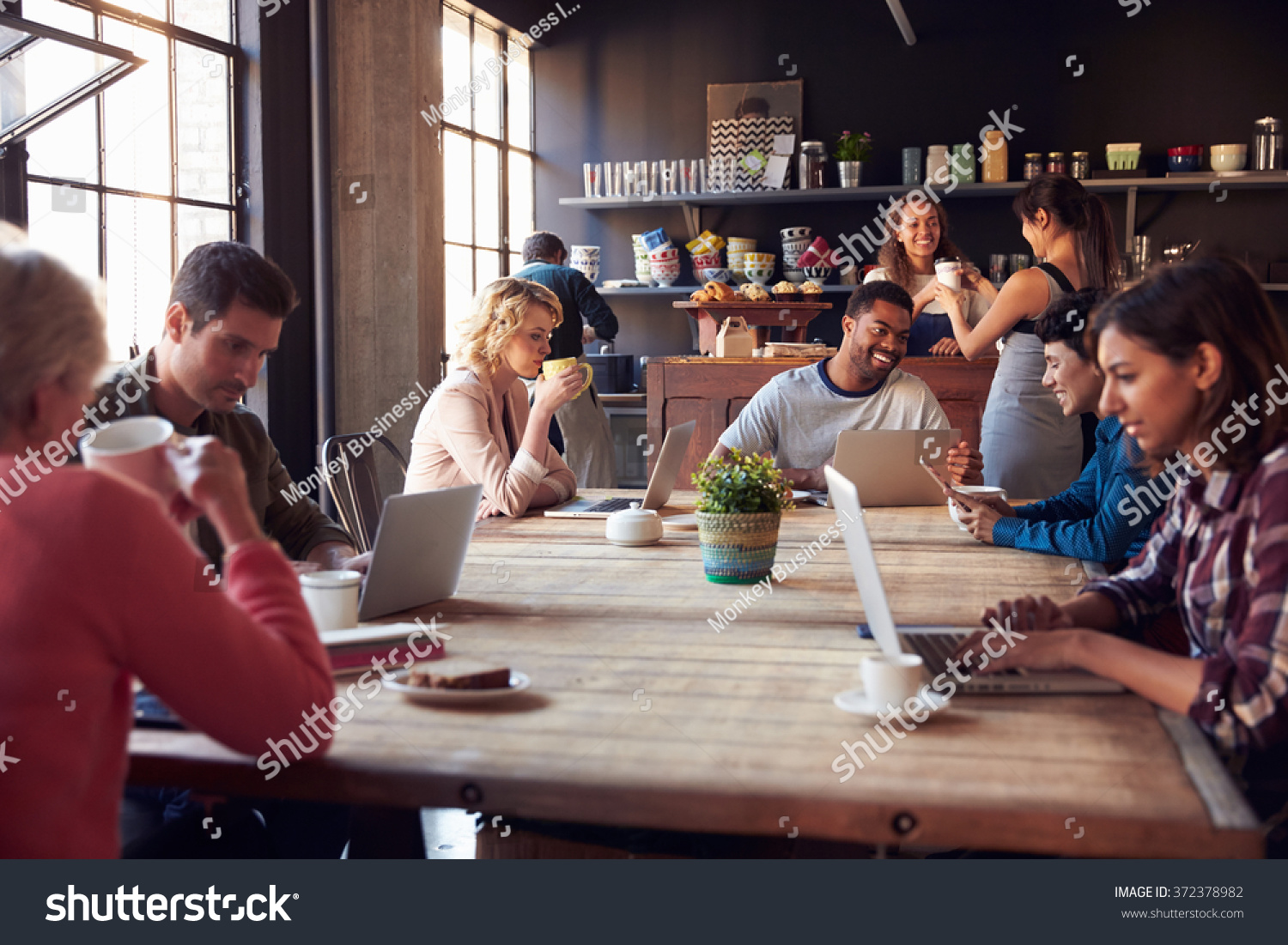 Interior Of Coffee Shop With Customers Using Digital Devices #372378982
