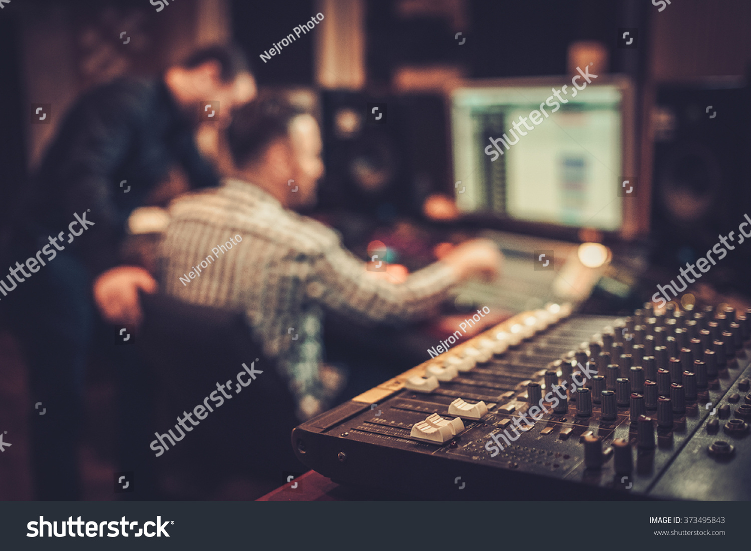Sound engineer and producer working together at mixing panel in the boutique recording studio. #373495843