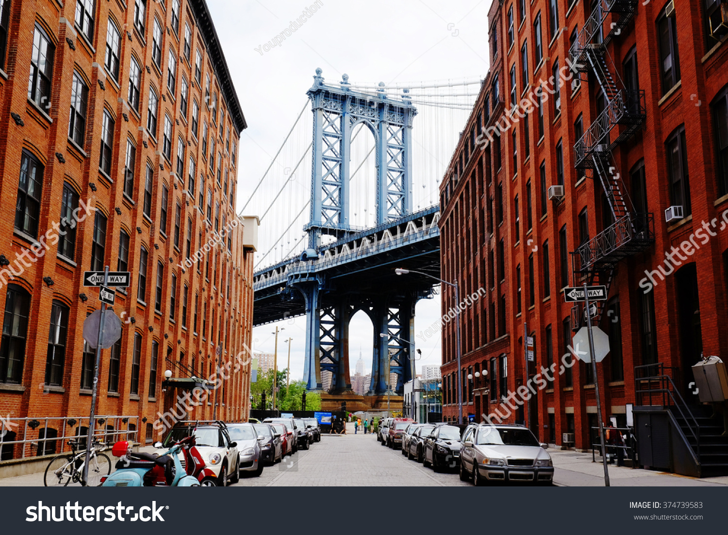 Manhattan bridge seen from a red brick buildings in Brooklyn street in perspective, New York, USA. Beautiful classic apartments in New York City. Beautiful american street. Famous view. #374739583