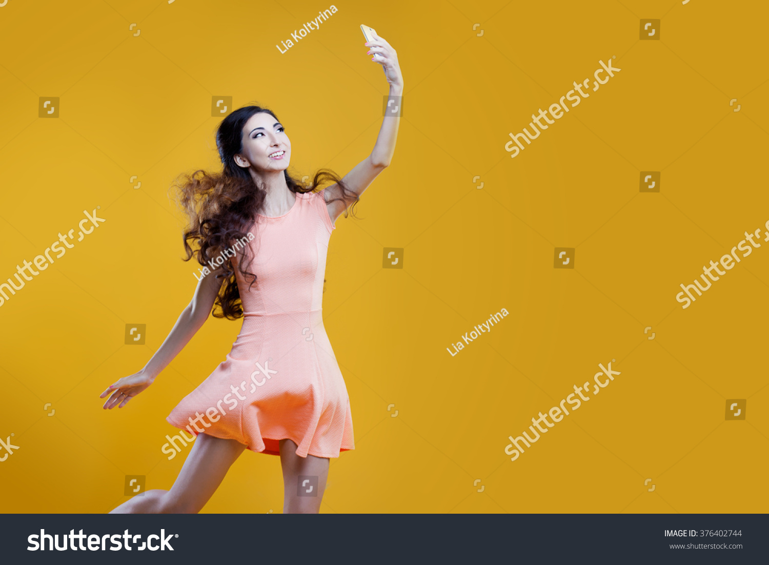 Fashion asian young  girl   taking picture of herself, selfie. Yellow background. place for your text on the right #376402744