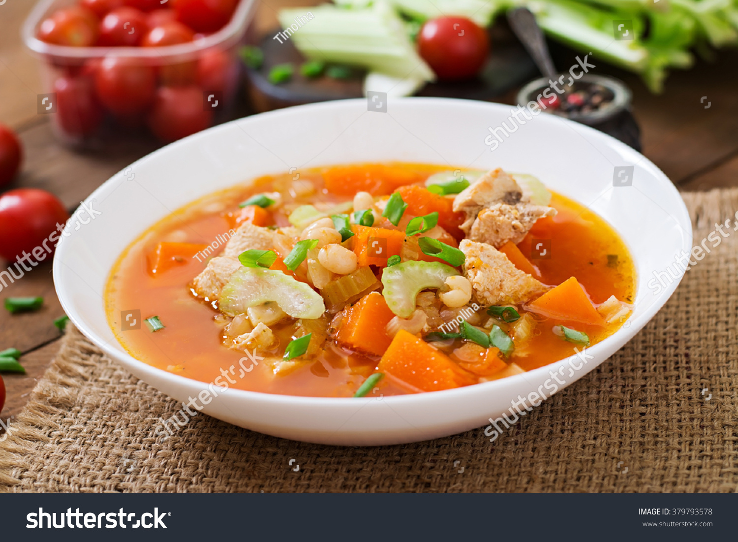 Tomato chicken soup with pumpkin, beans and celery in white bowl #379793578