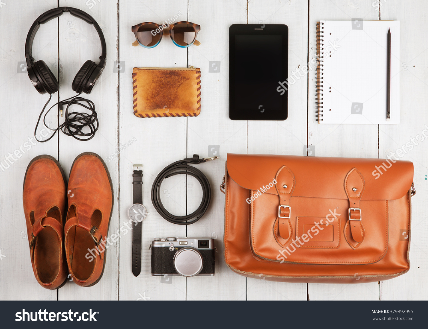 Travel concept - tablet pc, headphones, camera, shoes, watch and bag on the desk #379892995