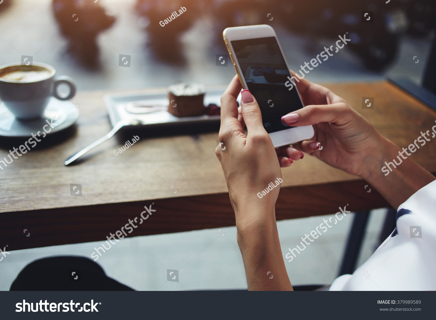 Close up of women's hands holding cell telephone with blank copy space scree for your advertising text message or promotional content, hipster girl watching video on mobile phone during coffee break  #379989589