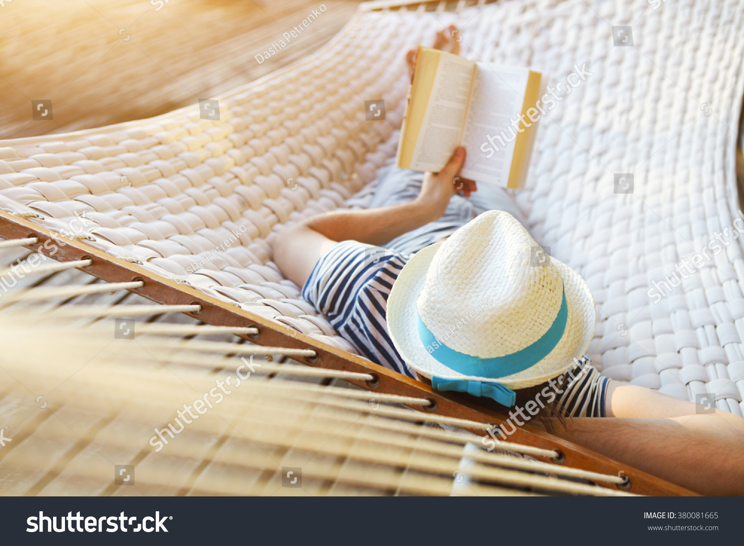 Lazy time. Man in hat in a hammock with book on a summer day #380081665